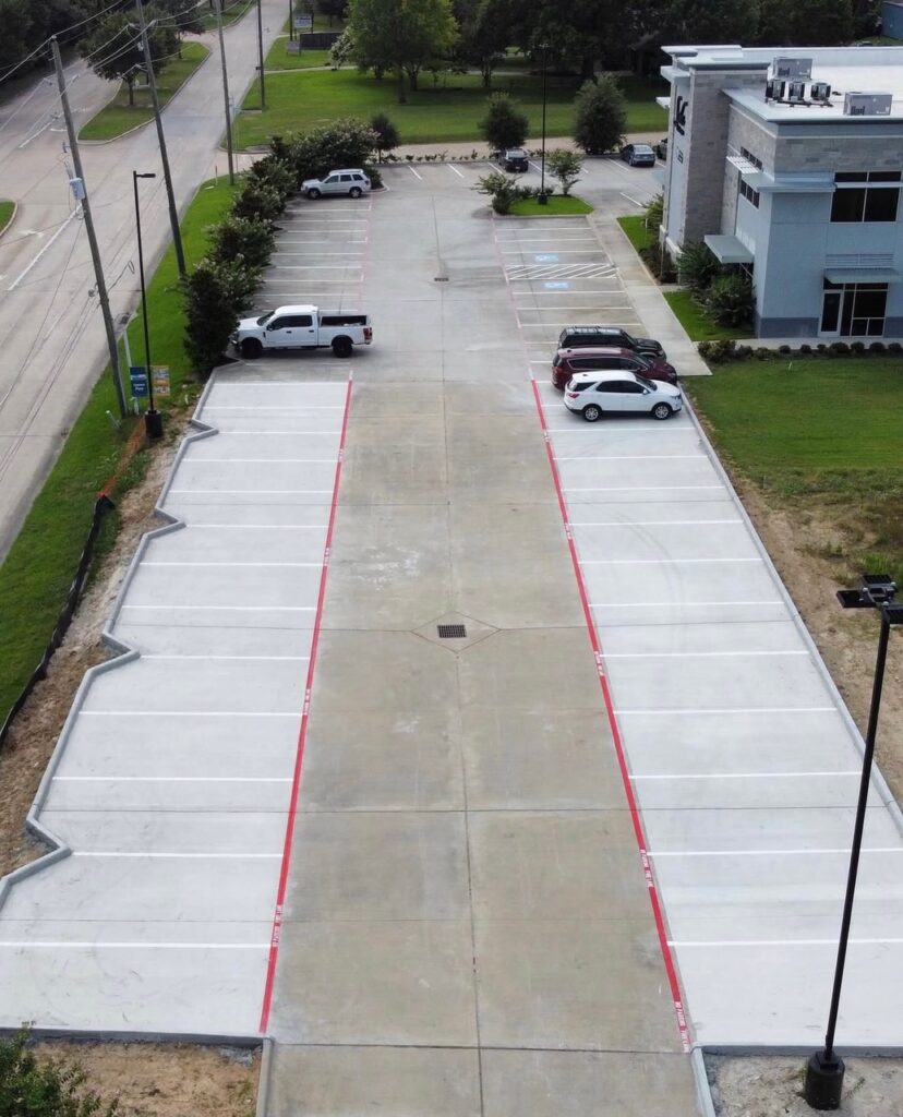 Empty office parking lot with two vehicles along green urban street - FMF Roofing