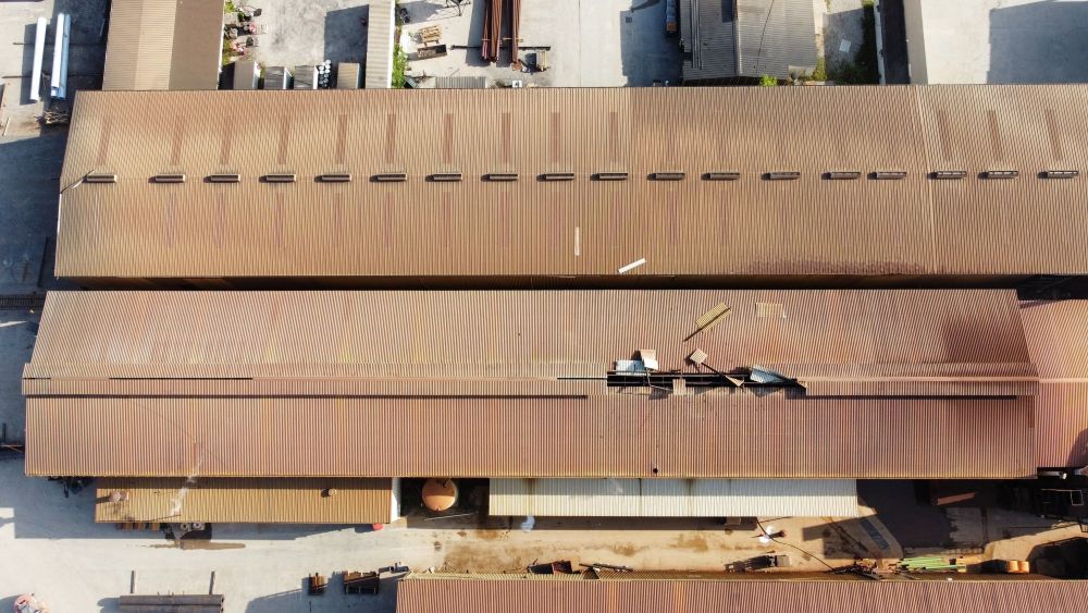 Aerial view of industrial warehouses with damaged roof - FMF Roofing